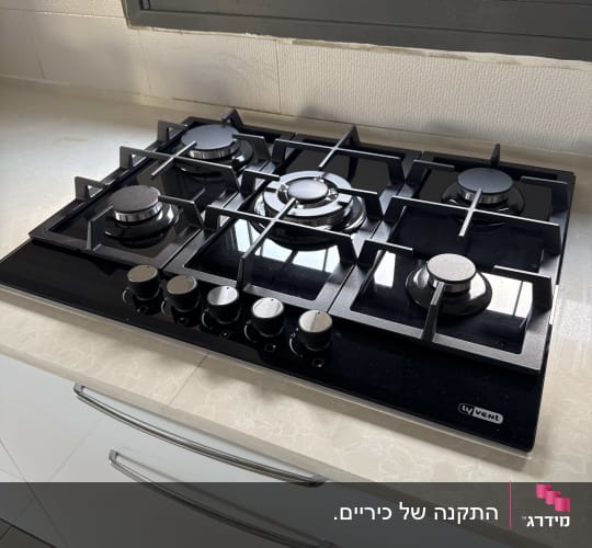כיריים גז שחורות עם חמישה מבערים במטבח מודרני